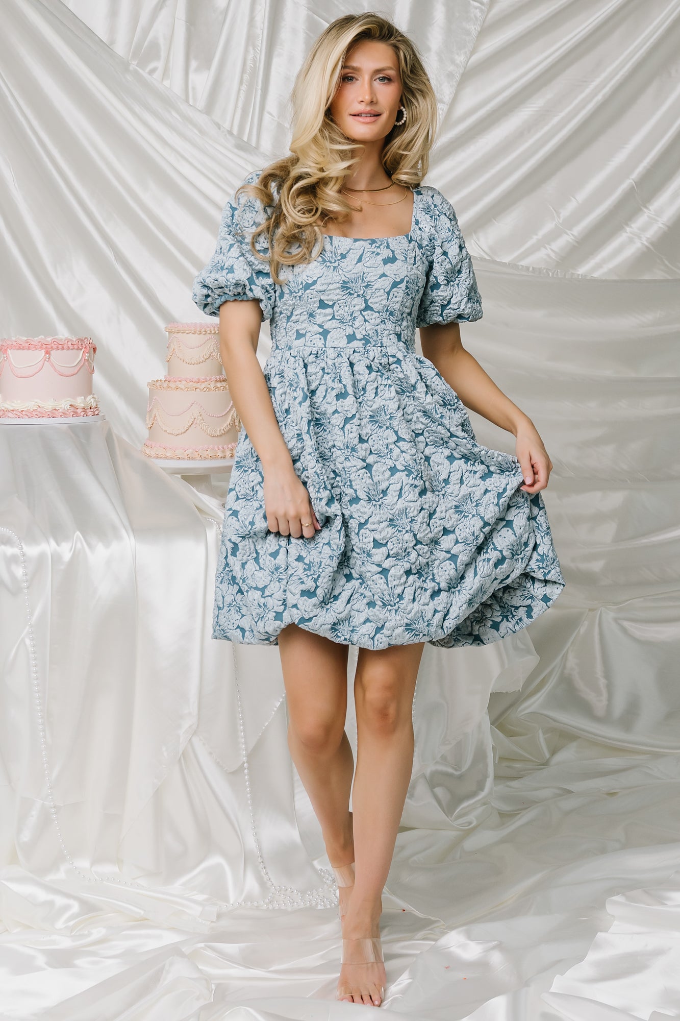 Close-up detail of the dusty blue jacquard fabric showing raised floral texture and subtle shimmer in the woven pattern.