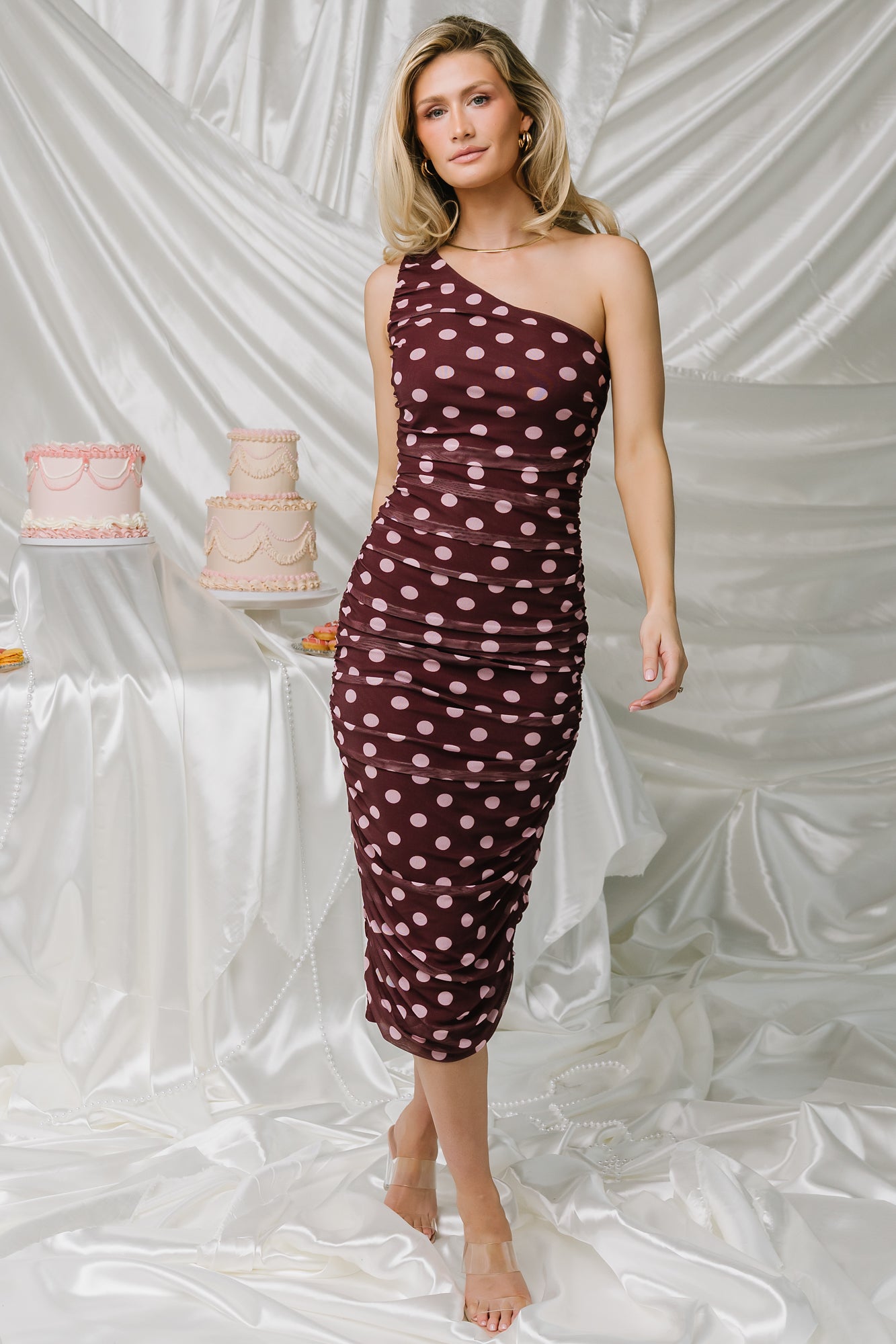Close-up of fabric showing sheer stretchy mesh with a maroon base, light pink polka dots, and fine ruching detail.