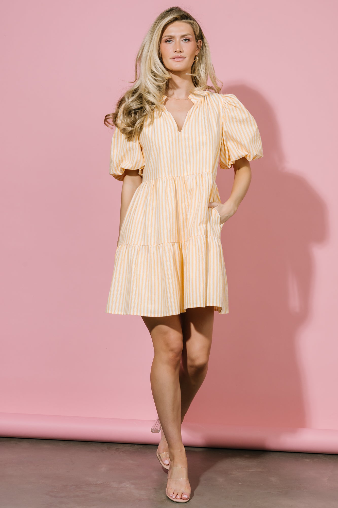Close-up of the ruffled V-neck trim and lightweight cotton fabric with off-white and soft orange stripes on the Sadie Short Dress.