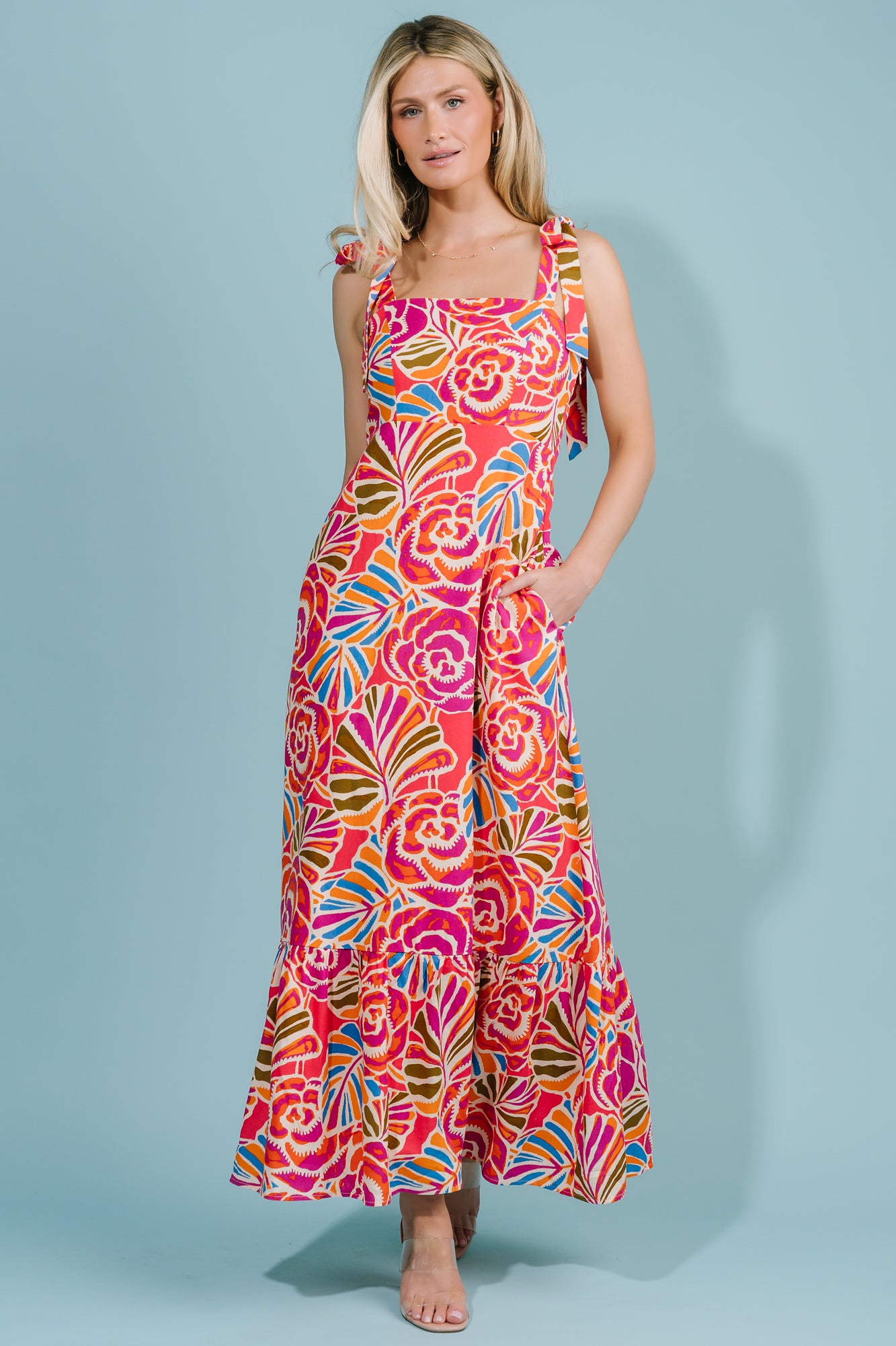 Close-up of fabric showing vibrant pink, orange, blue, and green floral print on a cream base and the lightweight rayon-linen texture.