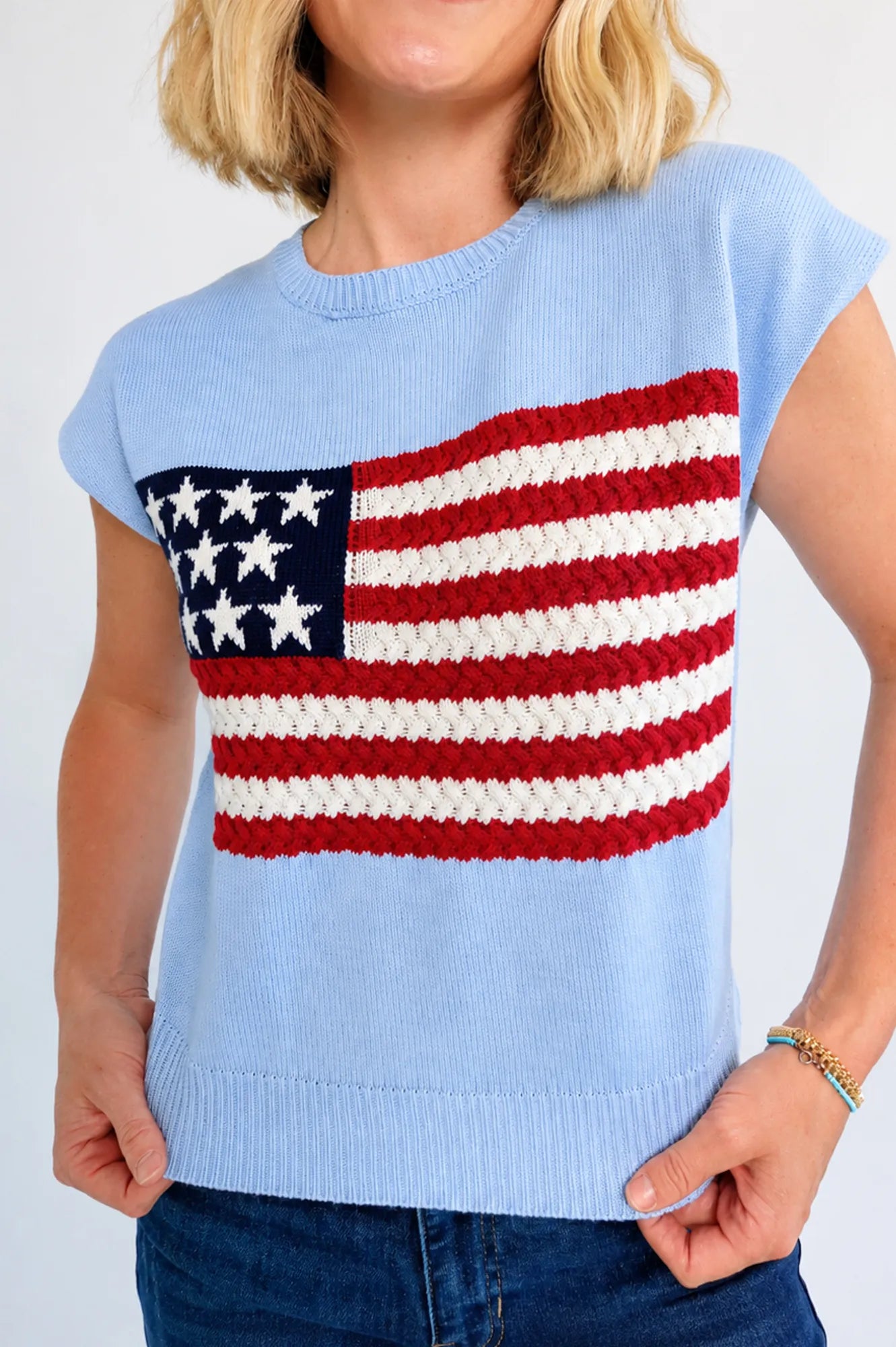 Model wearing a sleeveless knit with flag sweater top