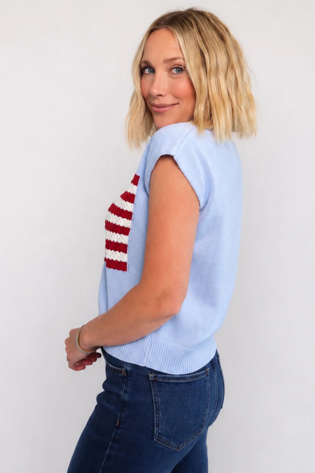 Model wearing a sleeveless knit with flag sweater top