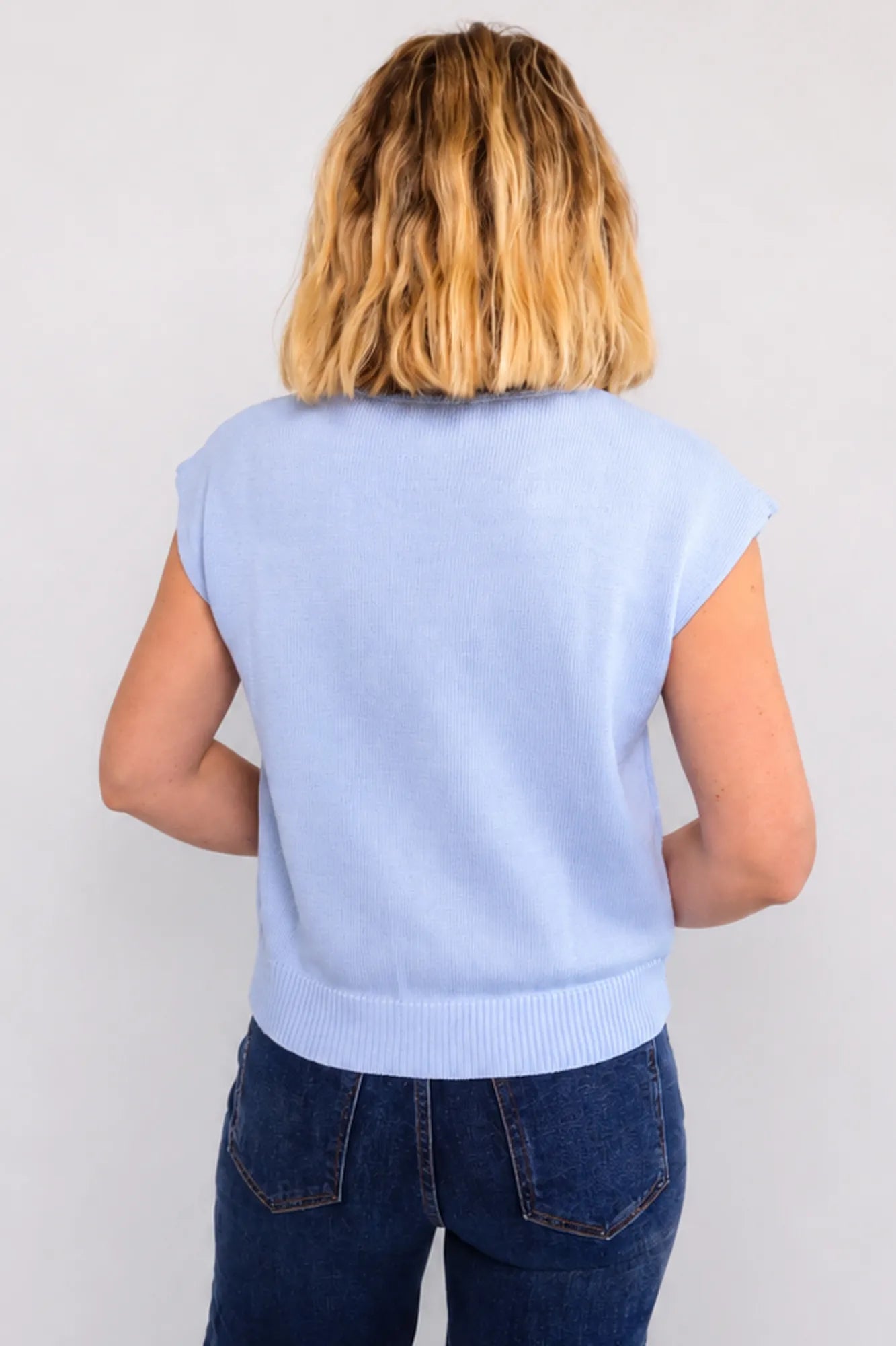 Model wearing a sleeveless knit with flag sweater top