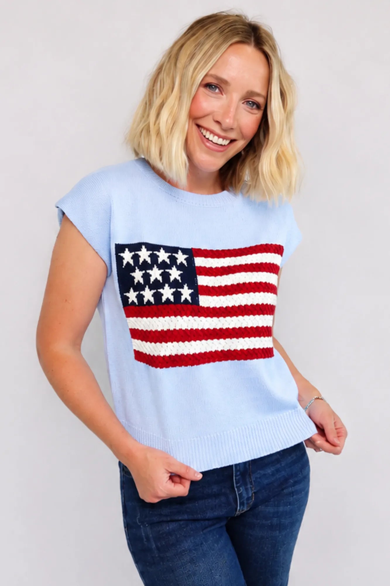 Model wearing a sleeveless knit with flag sweater top