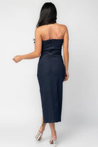 Back view of model showcasing the Caldwell Denim Midi Dress in Dark Wash, strapless dark navy denim midi dress with a pleated bust