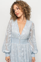 Close-up detail of functional flower buttons and delicate burnout floral texture on the light blue Daniella chiffon dress bodice.