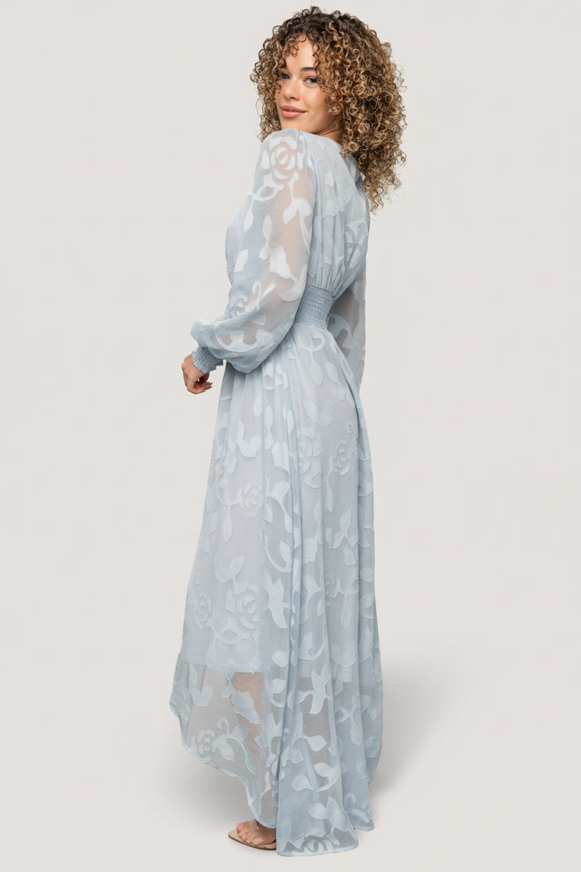Model shot of the Daniella dress in motion, showing the flowing high-low skirt and soft drape of the burnout floral chiffon fabric.
