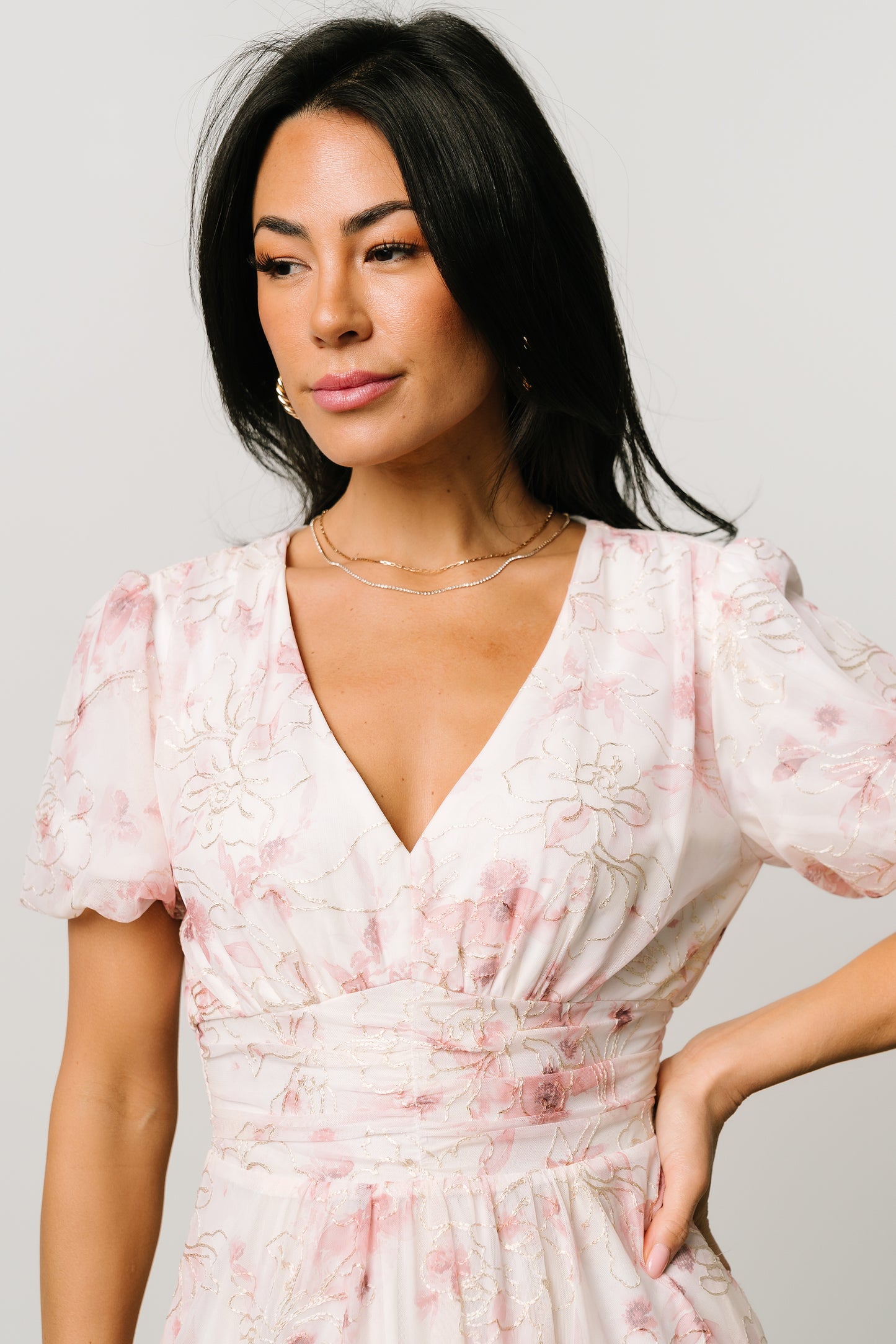 Close-up of bodice highlighting the V-neckline, short puff sleeves, gathered waist, and delicate gold-cream embroidered pattern on mauve floral fabric.