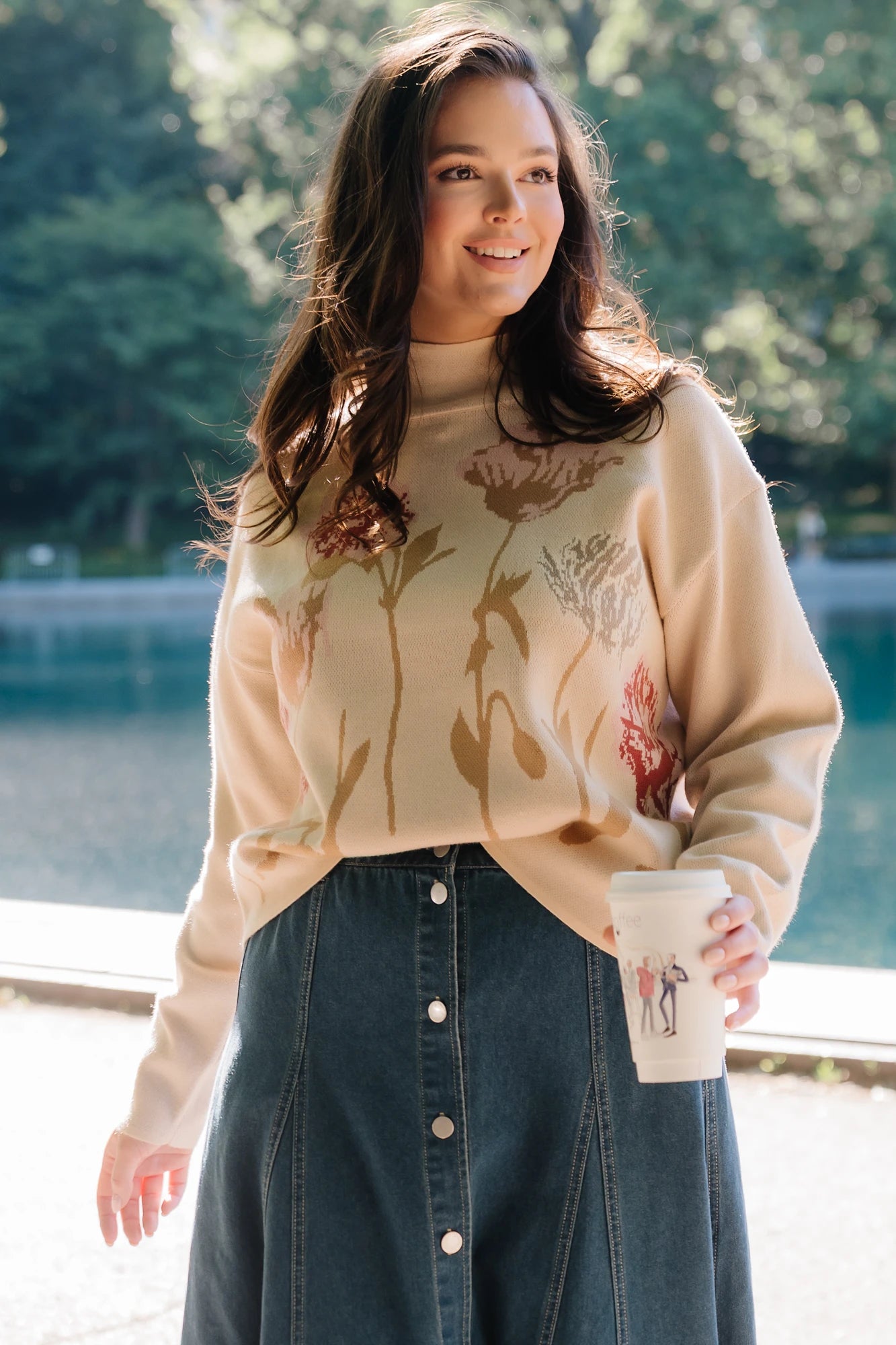 Natural knit sweater with a mock neckline, long sleeves, relaxed fit, and an embroidered floral motif at the neckline.