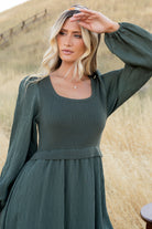Styled outfit shot of the Alva Sweater Dress in dusty green paired with casual footwear, emphasizing day-to-night versatility and practical pockets.