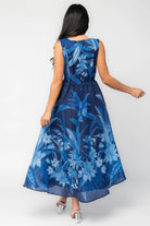 Model wearing a navy sleeveless midi dress with a high boat neckline and a fitted bodice. A tonal blue floral print adds subtle dimension throughout, while the defined waist flows into a full midi skirt that creates graceful movement and an elegant, timeless silhouette.