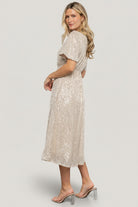 Model styled for evening with minimal jewelry and heels, showing how the champagne sequin midi dresses for celebrations.