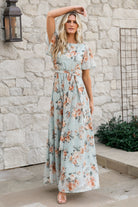Front view of Katalaya Maxi Dress in soft sage with muted gold floral embroidery on a tulle overlay, full-length skirt and flutter sleeves.