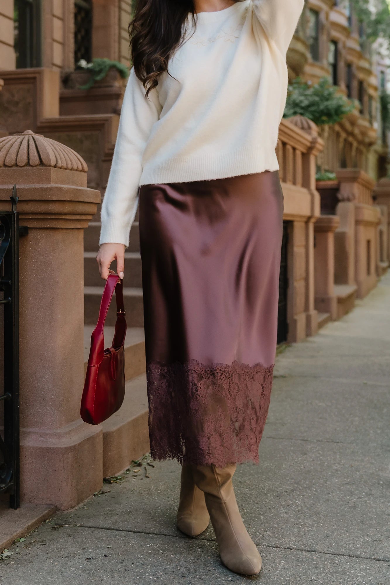 Model wearing the Kamara Satin Lace Skirt in Chocolate featuring a high-rise waistband, bias-cut satin silhouette, delicate floral lace trim at the hem, and a flowing midi length.