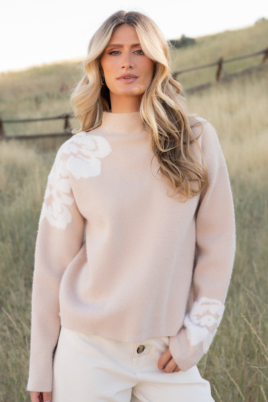 Side view of the sweater highlighting boxy silhouette, mock neckline, long sleeve, and wide knit cuff at the wrist.