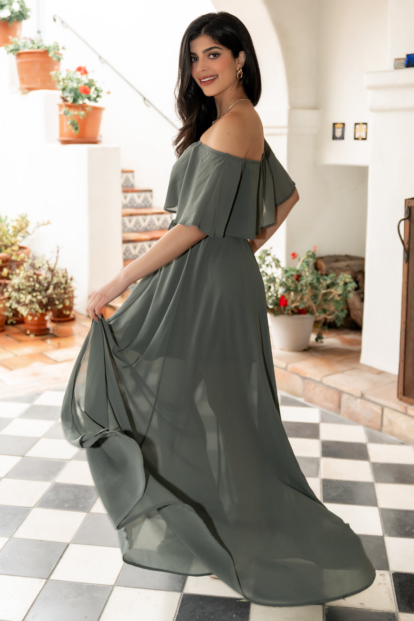 Model walking in dark sage maxi dress to show movement and drape, elastic waist shaping and airy polyester fabric in motion.