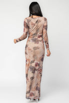 Model wearing a dark taupe floral maxi dress with a fitted bodycon silhouette, sheer long sleeves, and a round neckline.
