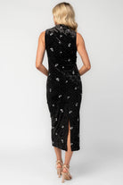 Model wearing a black velvet midi dress with a high neckline and fitted silhouette.