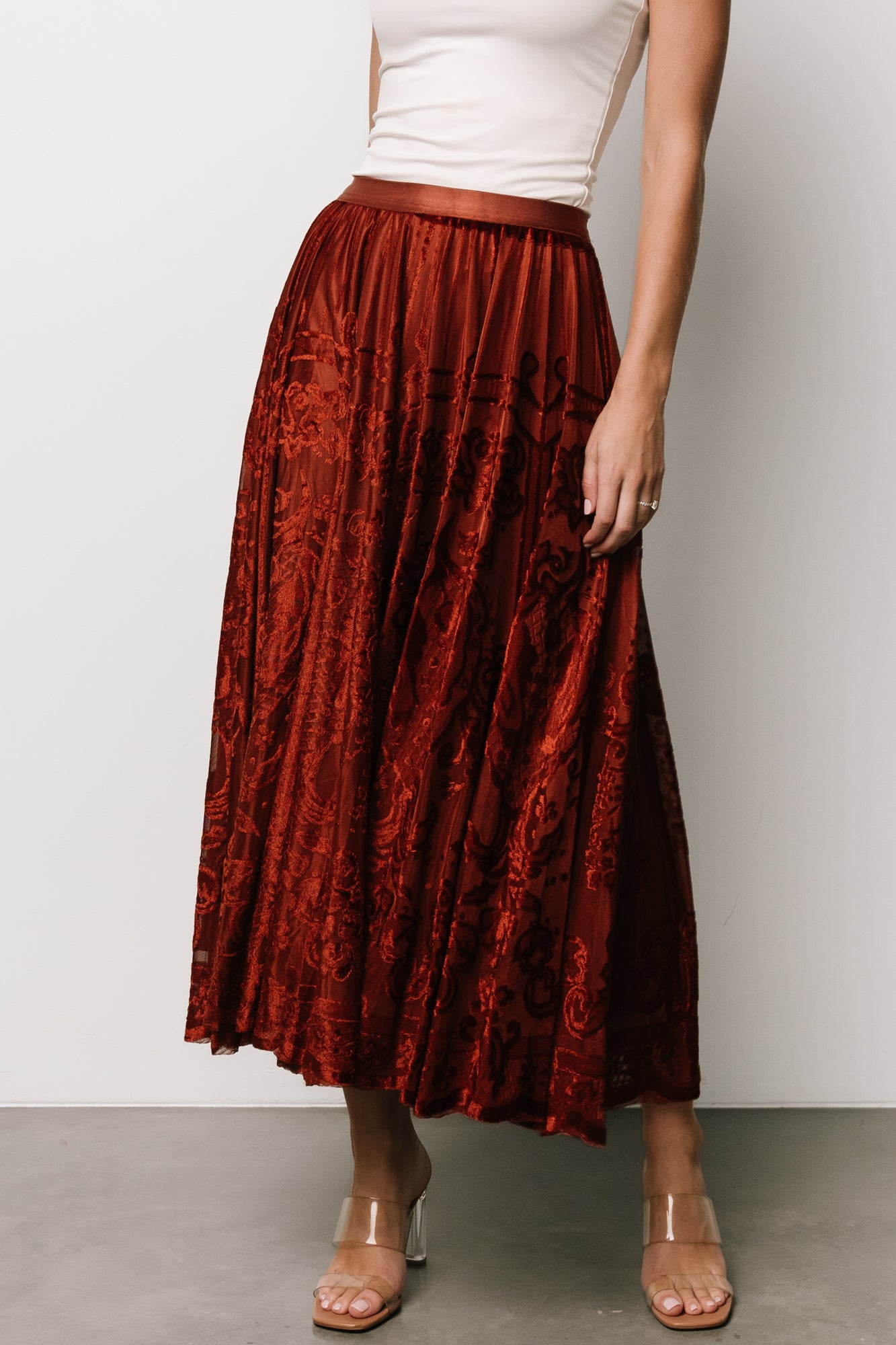 Front model view of Palini rust velvet burnout midi skirt showing elastic waistband and flowing drape, fully lined.
