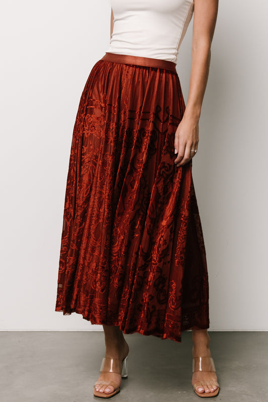 Front model view of Palini rust velvet burnout midi skirt showing elastic waistband and flowing drape, fully lined.