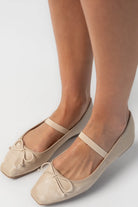 Pair of taupe velvet Mary Jane ballet flats featuring a square toe, delicate bow detail, and elastic strap across the foot. The classic flat silhouette offers a timeless, feminine look for everyday wear.