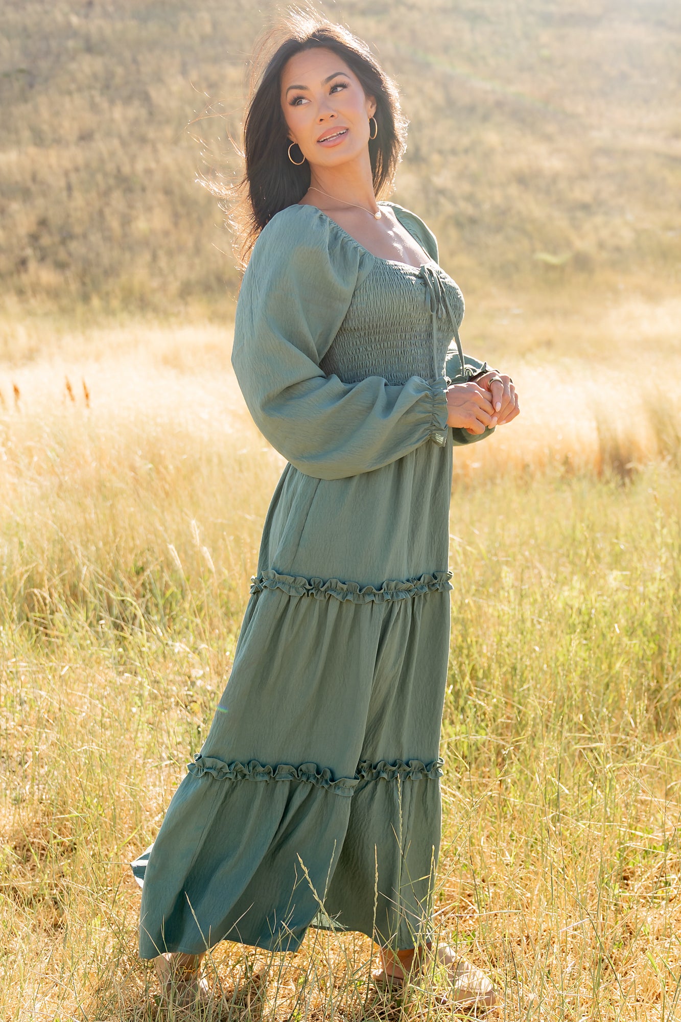 Styled detail shot of the dark sage Britta Maxi Dress focusing on fabric texture, smocking, and the delicate bow cinch at the neckline.