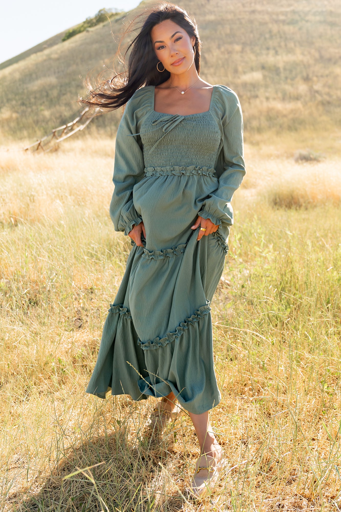Full-length shot of the Britta Maxi Dress in dark sage showing three-tier ruffle skirt and natural drape in soft lighting.