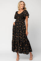 Model wearing a floral midi dress with a smocked bodice, wide V-neckline, and flutter sleeves.