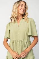 Model wearing a sage green midi dress with a collared neckline, button-front bodice, and short flutter sleeves.