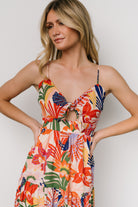 Model wearing Jaide midi dress in multi print walking pose, showing V-neckline, adjustable tie, and three-tier flow of the chiffon skirt.