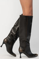 Pair of black knee-high boots featuring a pointed toe, sleek fitted shaft, and sculpted kitten heel. The streamlined silhouette and smooth finish create an elegant, versatile look that pairs effortlessly with dresses, skirts, and tailored outfits.