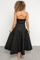 Rear view showing Selene's hidden back zipper and smooth full lining on a black strapless midi dress with textured floral motif.