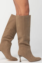 Pair of mocha knee-high boots featuring a pointed toe, sleek fitted shaft, and sculpted kitten heel. The streamlined silhouette and smooth finish create an elegant, versatile look that pairs effortlessly with dresses, skirts, and tailored outfits.