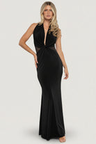 Three-quarter angle of the black halter gown highlighting sheer mesh side panels, fitted waist, and graceful skirt movement on a model.