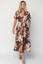 Model wearing the Blythe Midi Dress in Brown Floral featuring a collared neckline, functional button-front bodice, short rolled sleeves, and a removable waist tie.