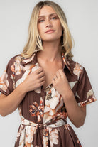 Model wearing the Blythe Midi Dress in Brown Floral featuring a collared neckline, functional button-front bodice, short rolled sleeves, and a removable waist tie.