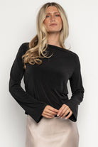 Lifestyle image of the black Tasia top on model, capturing the open back detail, boat neckline and elegant sleeve movement for event wear.