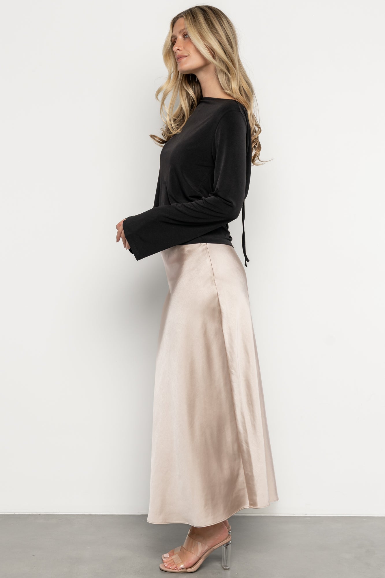Styled outfit photo with the Tasia Drape Back Top in black paired with a midi skirt, illustrating proportion, drape and evening styling options.