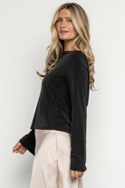 Close-up of the Tasia Drape Back Top in black, focusing on boat neckline, soft knit texture and the gentle flare of the bell sleeve.