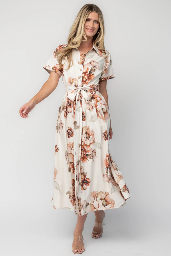Model wearing the Blythe Midi Dress in Ivory Floral featuring a collared neckline, functional button-front bodice, short rolled sleeves, and a removable waist tie.