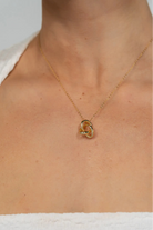 Model wearing a delicate gold-tone necklace featuring an interlocking infinity knot pendant suspended from a fine chain. The minimalist design sits at the collarbone for an elegant, everyday look.