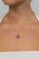Model wearing a delicate silver-tone necklace featuring an interlocking infinity knot pendant suspended from a fine chain. The minimalist design sits at the collarbone for an elegant, everyday look.