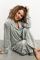 Model wearing Klara sage pajama set—long-sleeve ribbed velvet top with functional buttons and left chest pocket.