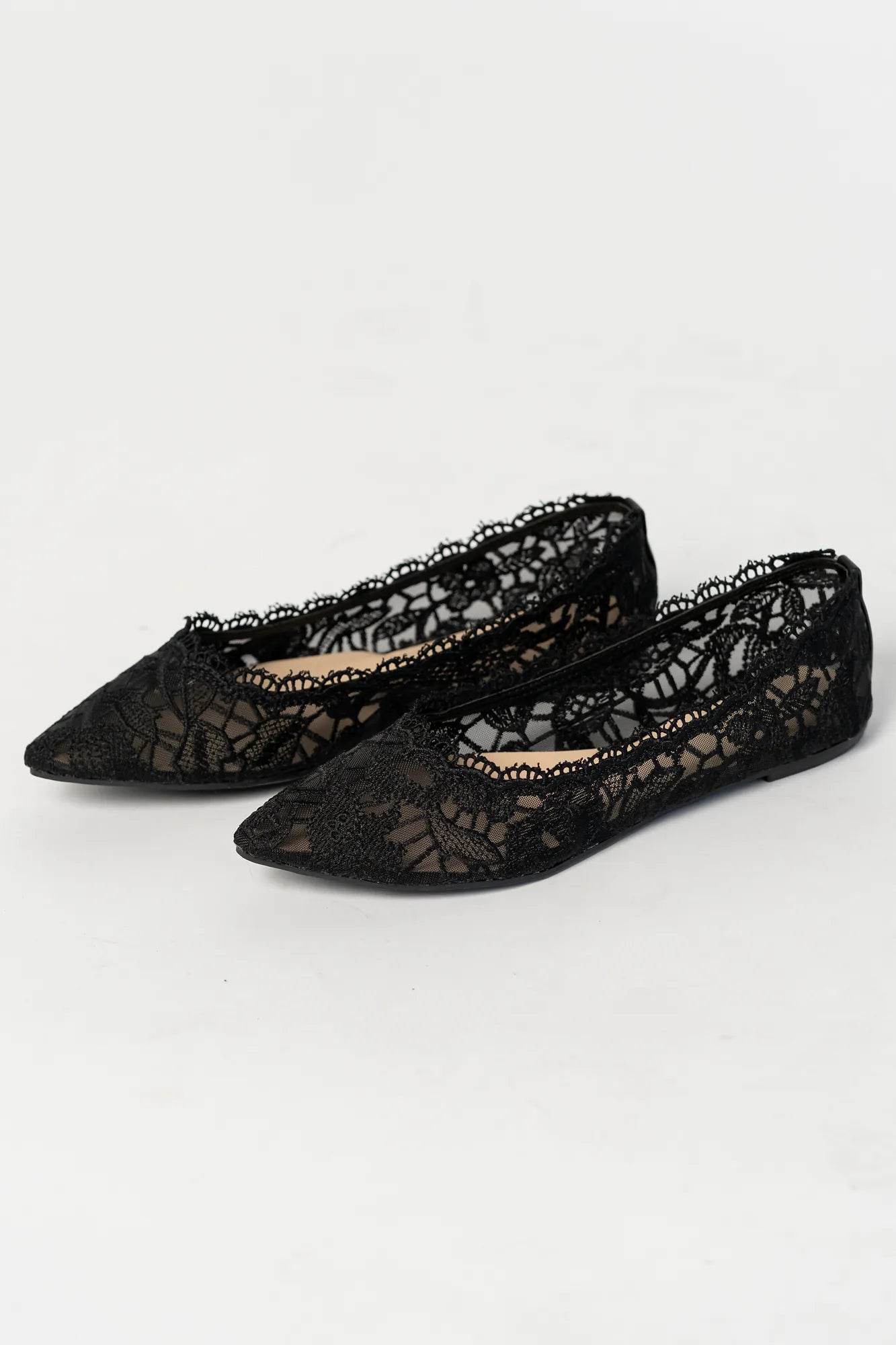 Lace ballet flats with a pointed toe, sheer lace construction, and scalloped edges. The feminine flat silhouette offers an elegant, lightweight look.