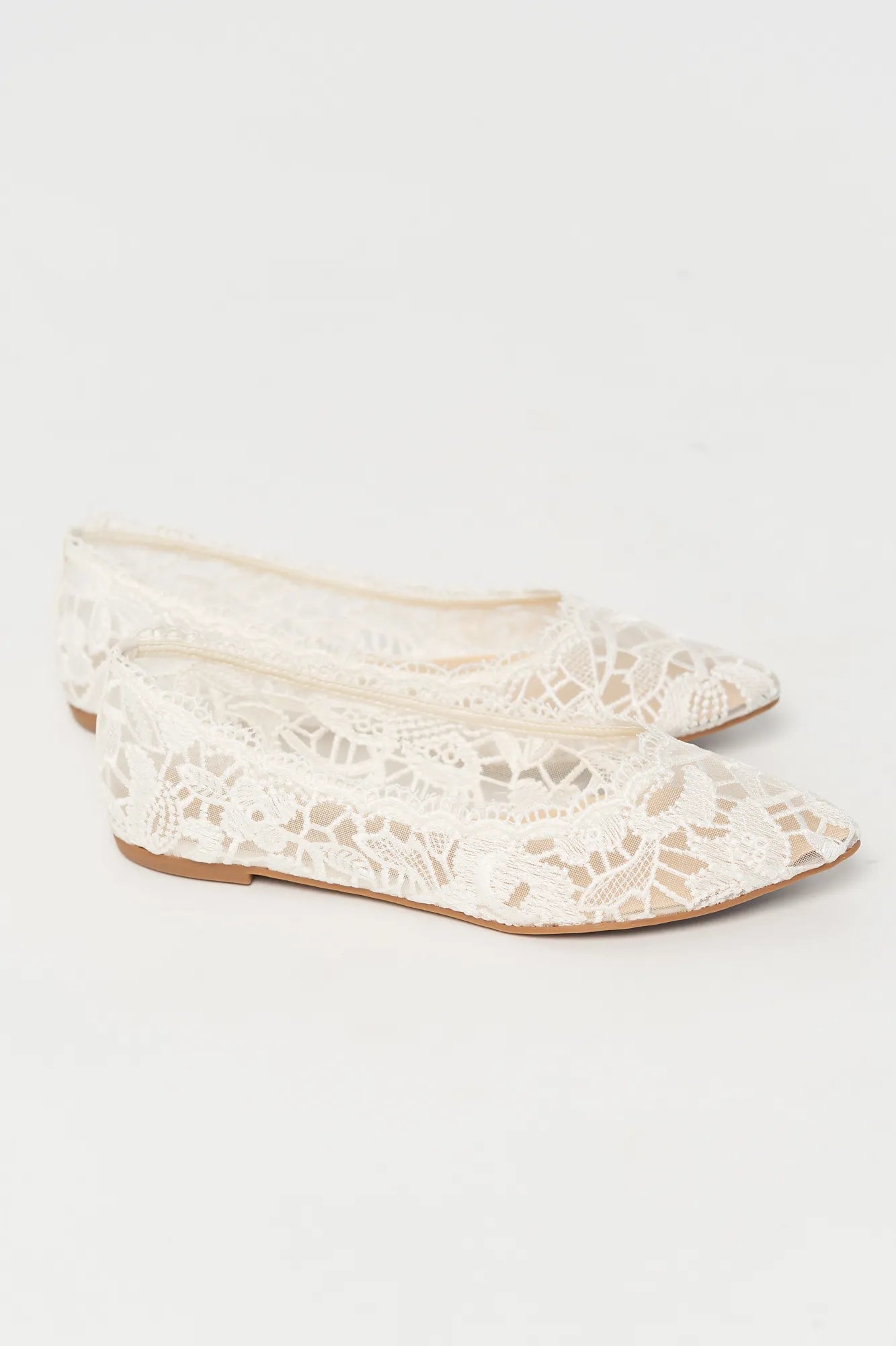 Ballet flats with a pointed toe, sheer lace construction, and scalloped edges. The feminine flat silhouette offers an elegant, lightweight look.