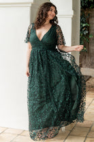 Side view of dark green maxi highlighting the left-leg slit, raw-cut hem, and the flow of the fully lined skirt as the model moves.