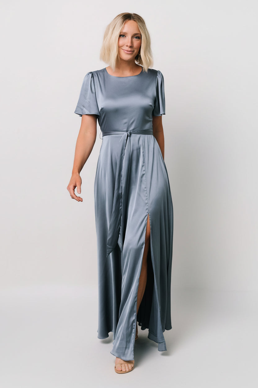Styled shot of the Agnes Satin Maxi Dress in whisper blue paired with heels, showing overall silhouette, flutter sleeves, and maxi-length sweep.