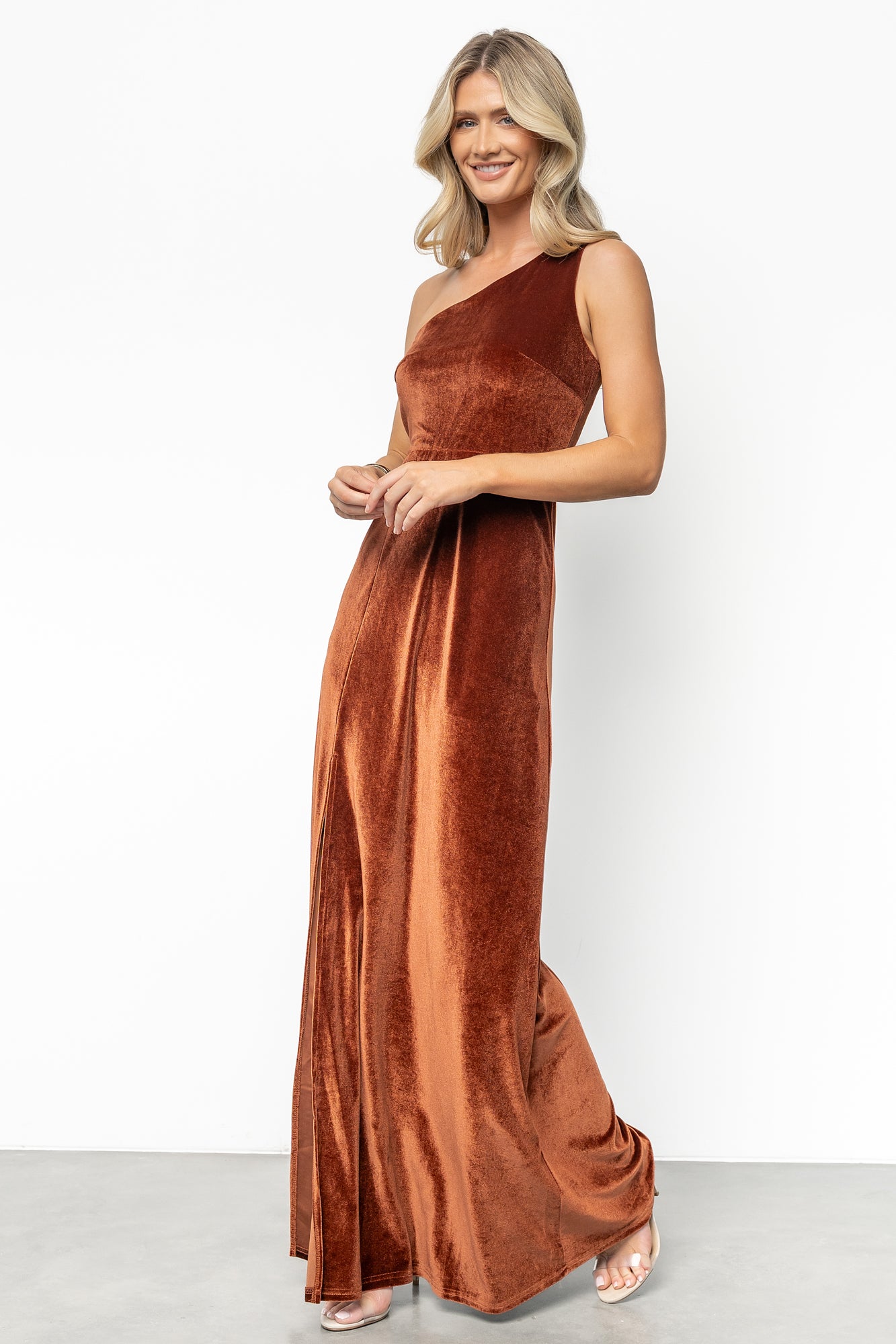 Side view of bronze velvet maxi on model emphasizing right-side slit to mid-thigh and the skirt’s gentle flare for ease of movement.