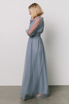 Model wearing Layla Tulle Maxi Dress in whisper blue walking pose that emphasizes the dress’s lightweight tulle movement and full-length maxi silhouette.