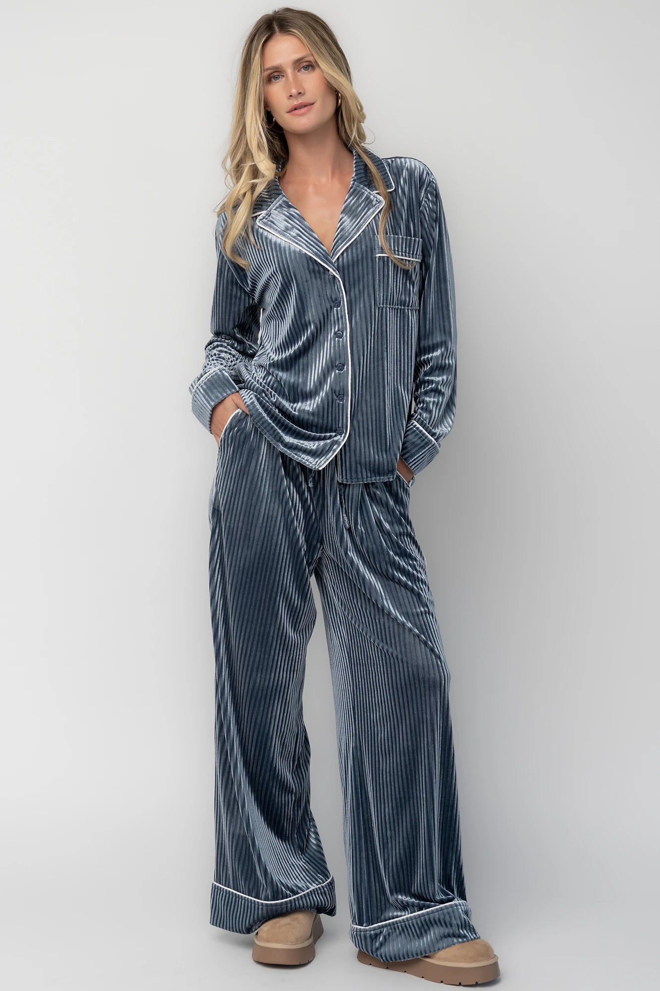 Dusty blue ribbed velvet pajama set with a collared button-front top, chest pocket, long sleeves, and wide-leg pants with an elastic drawstring waist and side pockets.